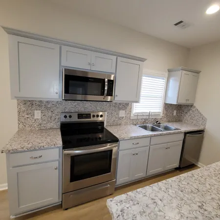 a kitchen with granite countertop a stove top oven microwave and cabinets