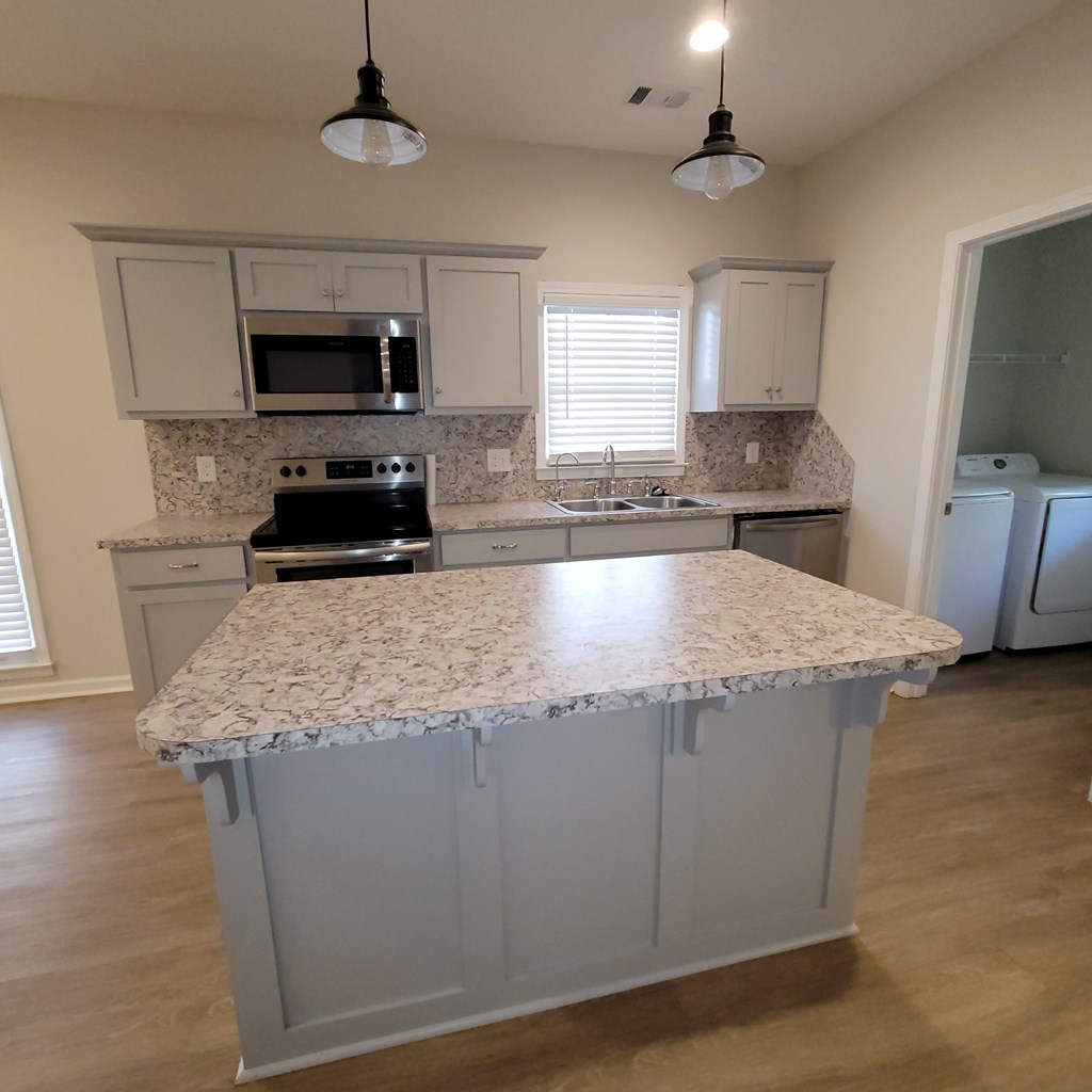 3604 4th Avenue Columbus, GA 31904 - Photo 7 of 19 a kitchen with kitchen island granite countertop a stove a sink a microwave and wooden cabinets
