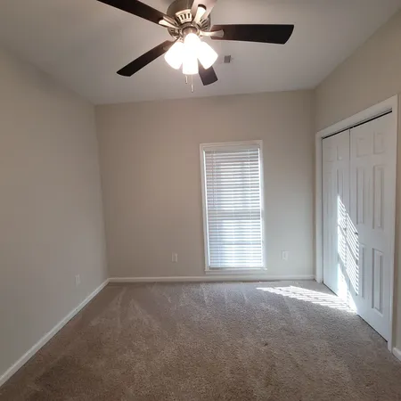 an empty room with windows and fan