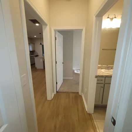 a view of a hallway with wooden floor and a bathroom