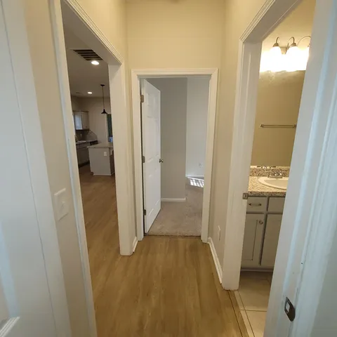 a view of a hallway with wooden floor and a bathroom