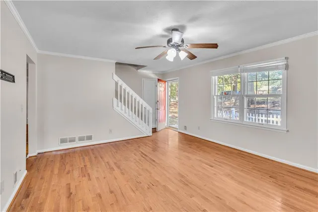 a view of an empty room with wooden floor and a window