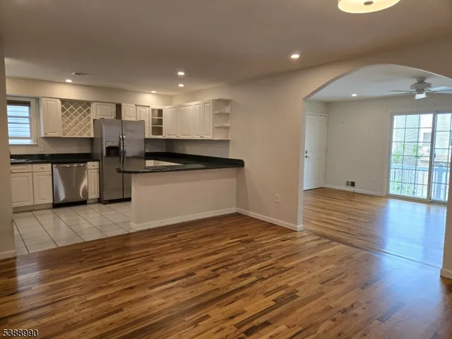 a view of a kitchen with kitchen island a sink wooden floor and stainless steel appliances