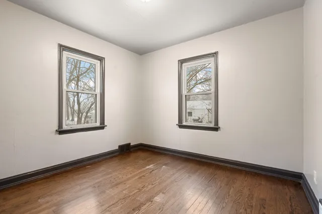 a view of an empty room with window and wooden floor