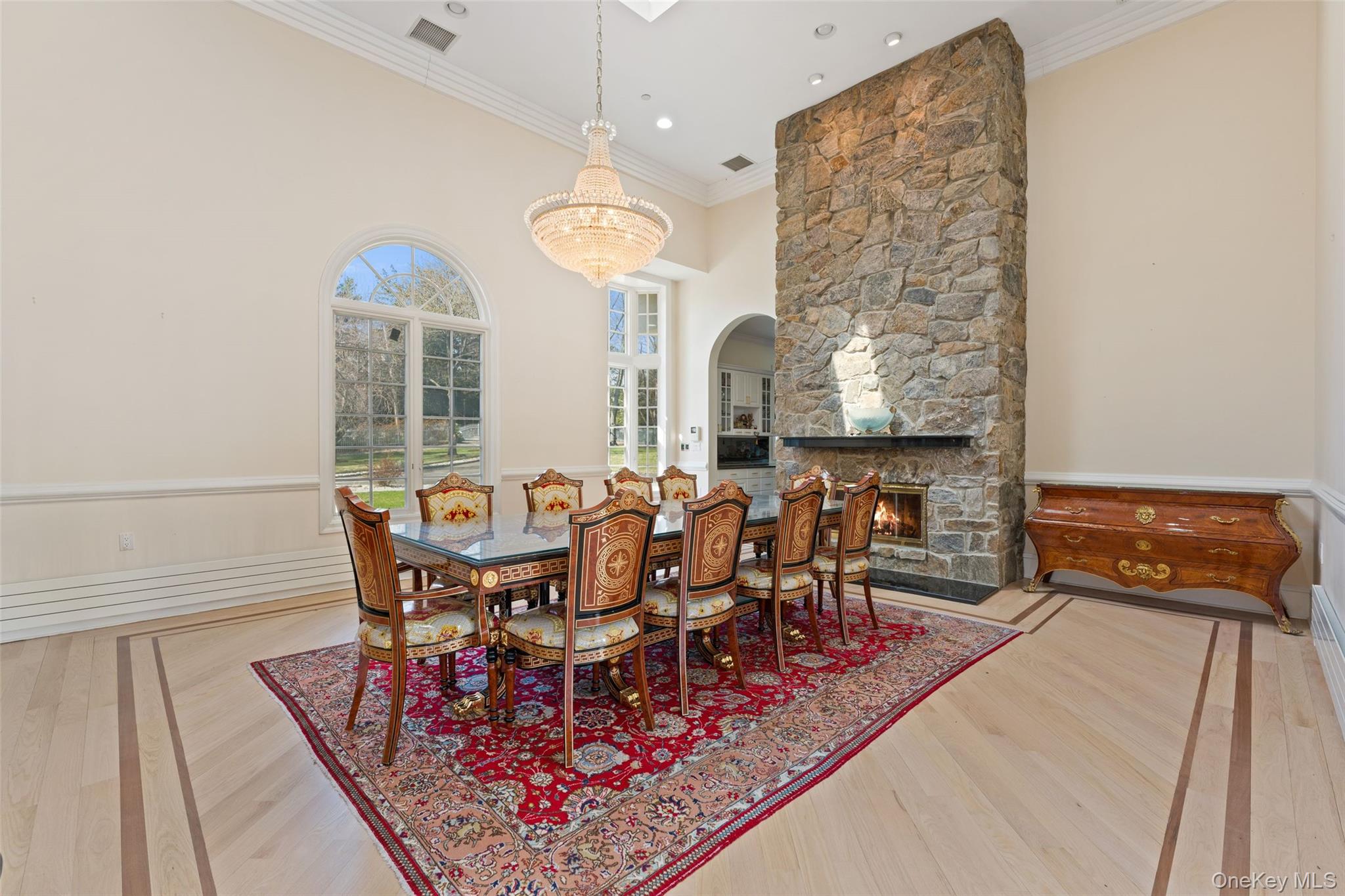2 High Point Terrace Scarsdale, NY 10583 - Photo 6 of 42 Dining area featuring hardwood floors with an inlaid border, a stone fireplace, and arched windows
