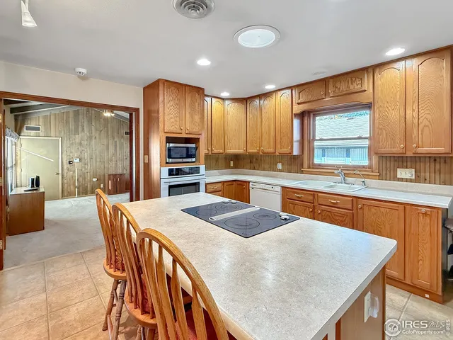 a kitchen with stainless steel appliances granite countertop a kitchen island a stove a sink a dining table and chairs