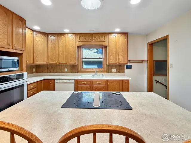 a kitchen with stainless steel appliances a stove a sink a refrigerator white cabinets and wooden floor