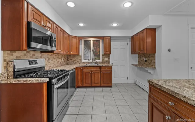 a kitchen with stainless steel appliances granite countertop a stove a sink and a microwave