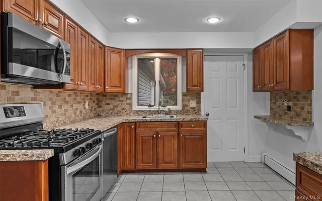 a kitchen with stainless steel appliances granite countertop a stove top oven a sink dishwasher and a microwave oven on the blue kitchen countertops