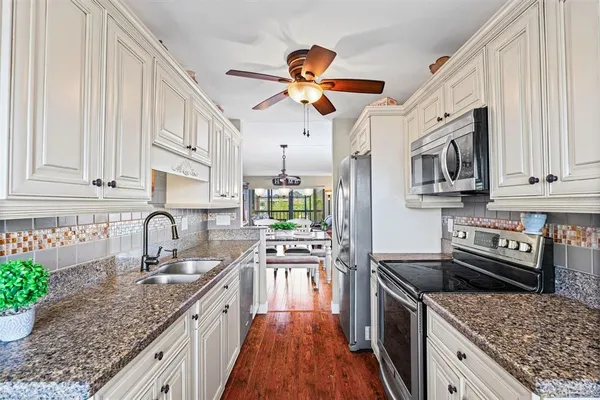 a kitchen with granite countertop a sink stainless steel appliances and cabinets