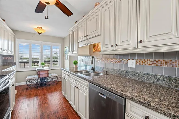 a kitchen with granite countertop a stove a sink and a refrigerator