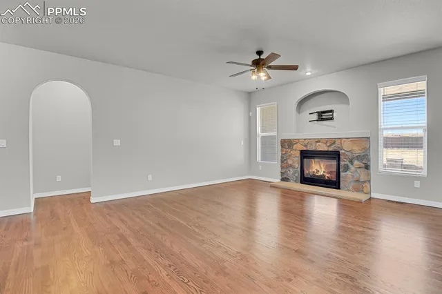 an empty room with fan fireplace and wooden floor