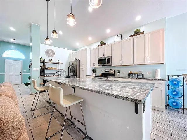 a kitchen with stainless steel appliances a stove a sink a kitchen island with a table and chairs