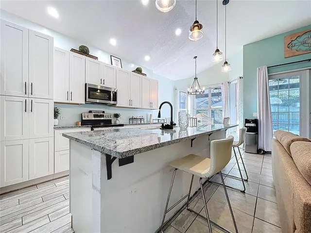 a kitchen with stainless steel appliances kitchen island granite countertop a stove a sink and a refrigerator