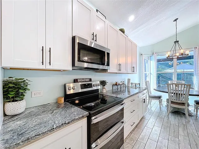 a kitchen with stainless steel appliances granite countertop a sink a stove and a microwave