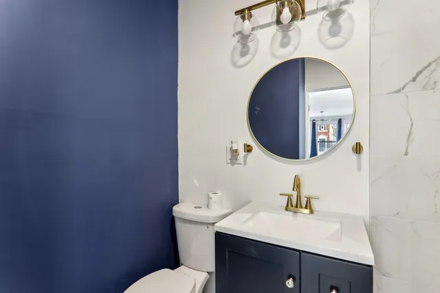 a bathroom with a toilet sink vanity and mirror