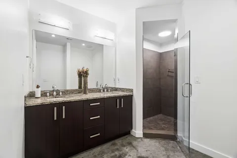 a spacious bathroom with a granite countertop sink a mirror and a shower