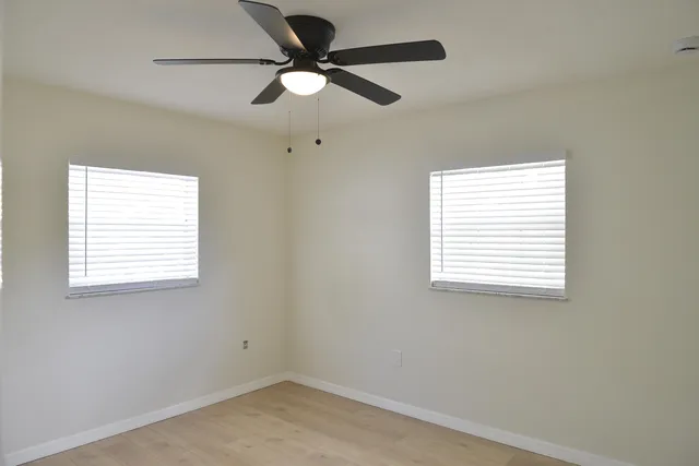 an empty room with a window and a fan