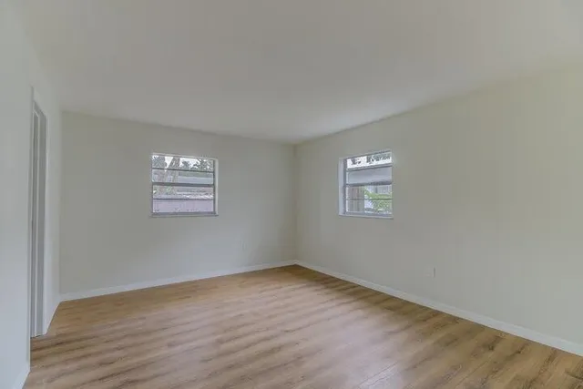 a view of an empty room with wooden floor and a window