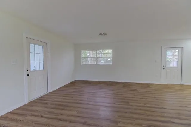 a view of an empty room with window and wooden floor