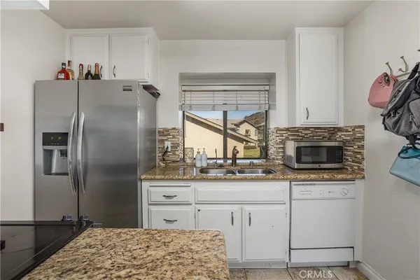 a kitchen with stainless steel appliances kitchen island granite countertop a refrigerator a stove and a sink