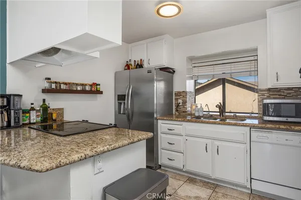 a kitchen with granite countertop a sink a stove and refrigerator