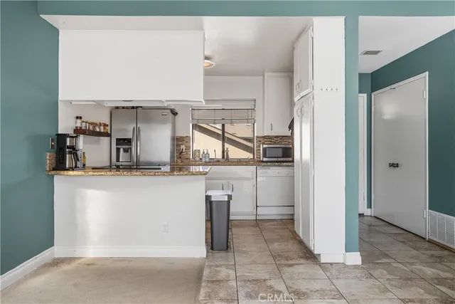 a kitchen with white cabinets and refrigerator