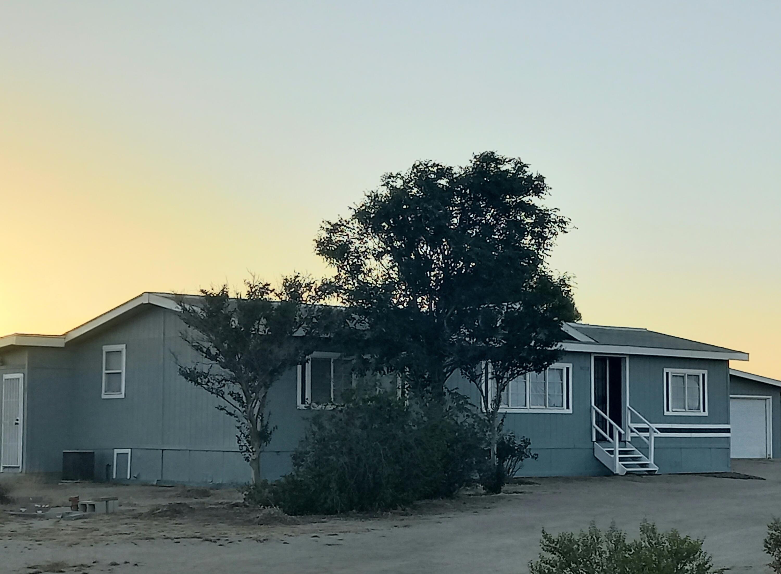 9073 Hull Street Mojave, CA 93501 - Photo 1 of 16 a view of a house with a tree and wooden fence
