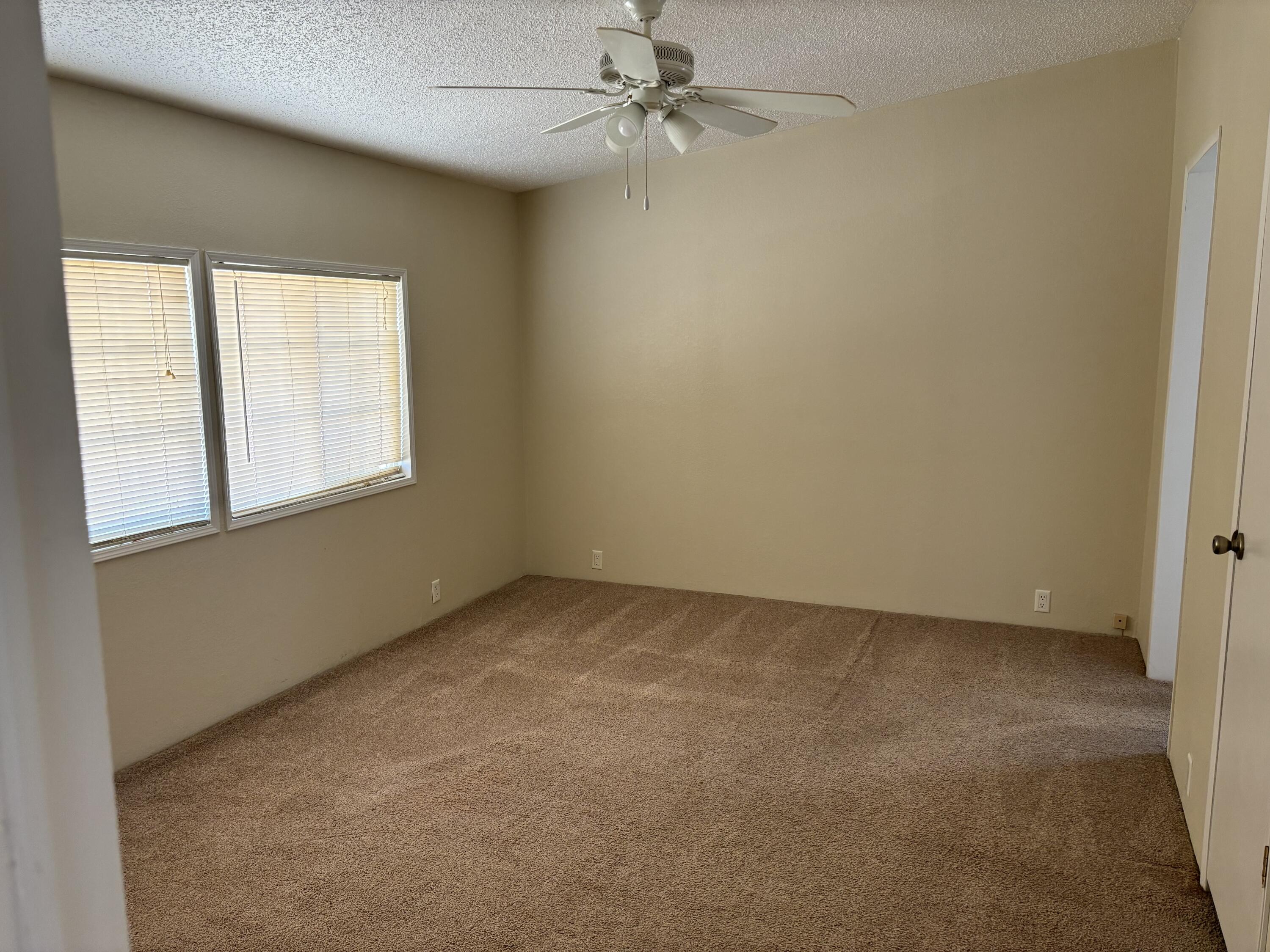 9073 Hull Street Mojave, CA 93501 - Photo 6 of 16 an empty room with a window and a fan
