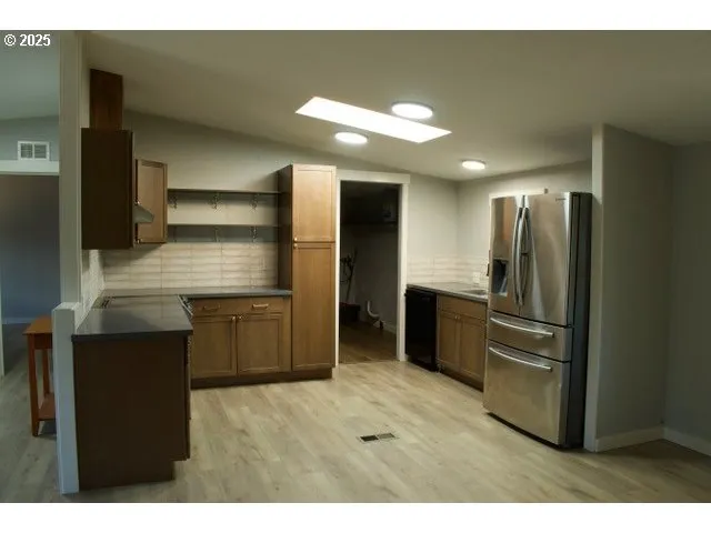 a kitchen with stainless steel appliances kitchen island granite countertop a refrigerator and a sink
