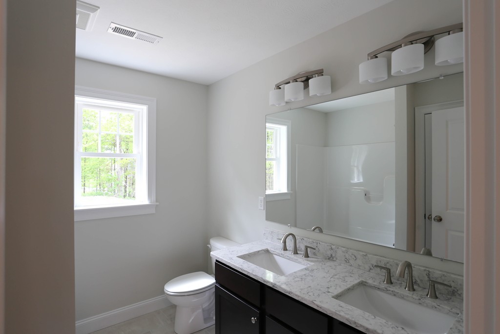 14 Spring Street Hopkinton, MA 01748 - Photo 11 of 16 a bathroom with a granite countertop sink a toilet and a mirror