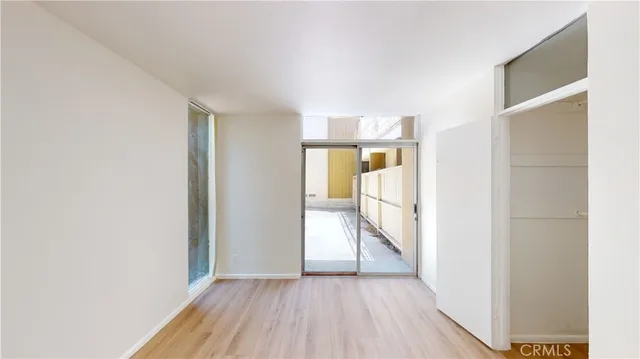 an empty room with wooden floor cabinet and windows