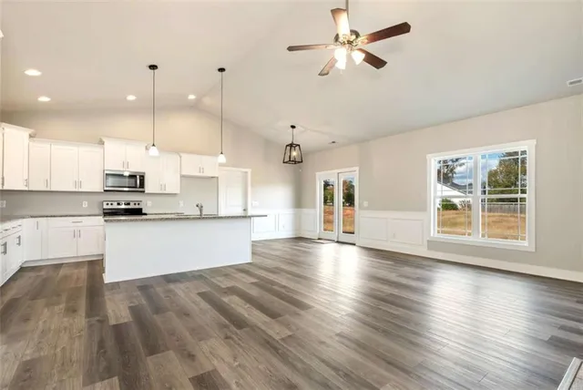 a large kitchen with granite countertop a stove top oven a sink a counter space and wooden floor