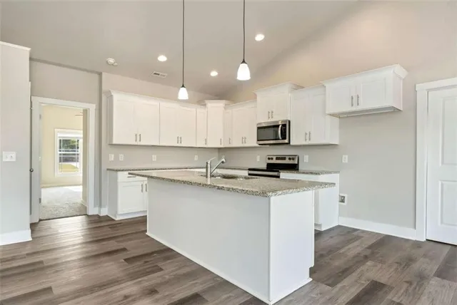 a kitchen with stainless steel appliances granite countertop a stove top oven a refrigerator a sink and dishwasher with wooden floor