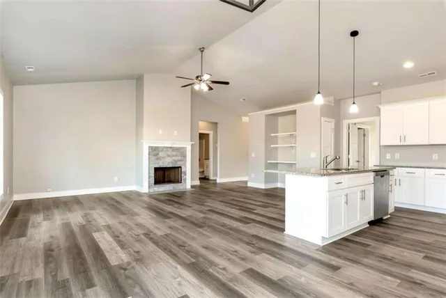 a large kitchen with granite countertop a stove top oven a sink dishwasher and a fireplace with wooden floor