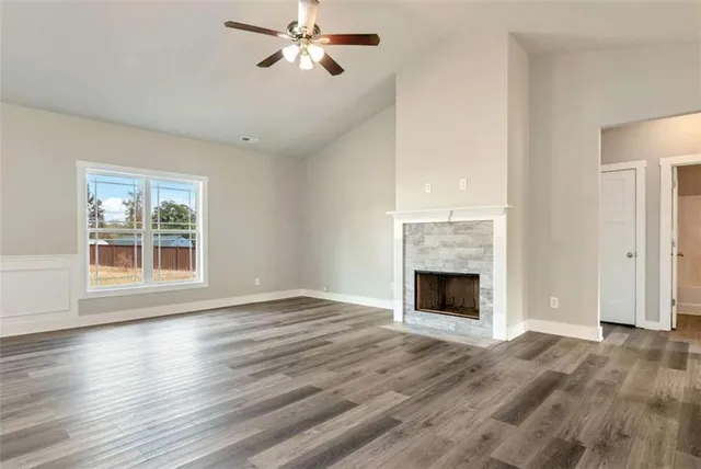 a view of an empty room with wooden floor fireplace and a window
