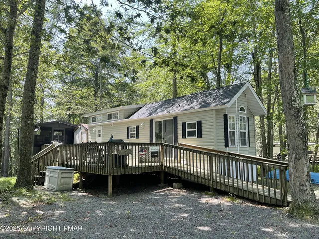 a view of a house with a wooden deck and a forest