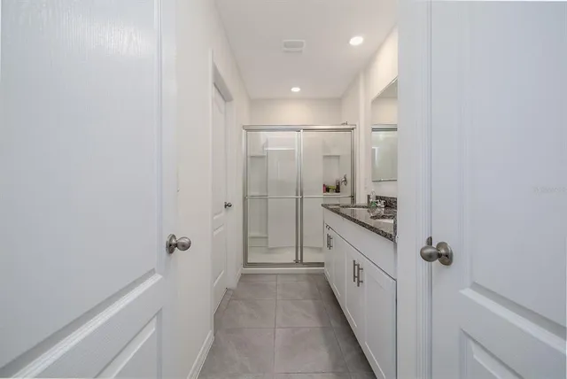 a bathroom with a granite countertop sink a mirror and a shower
