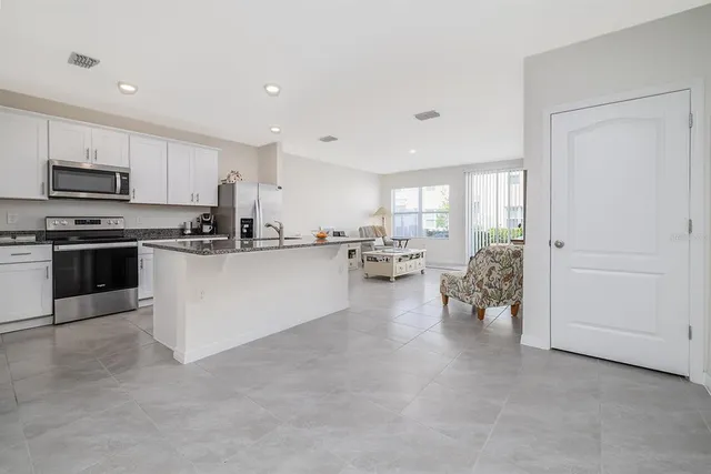 a kitchen with stainless steel appliances kitchen island granite countertop a stove top oven a sink a dining table and chairs