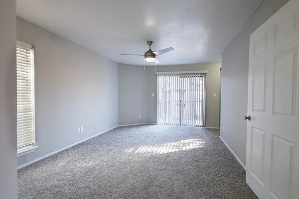an empty room with windows and chandelier fan