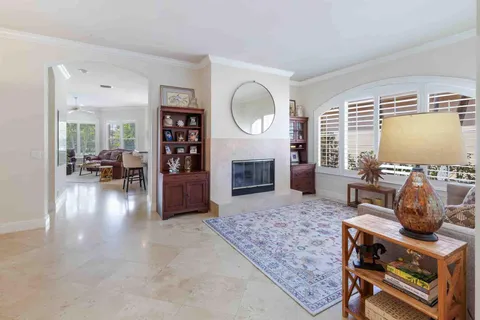 a living room with furniture a chandelier a potted plant and a large window