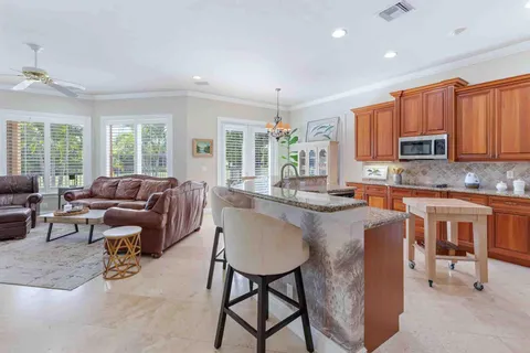 a kitchen with stainless steel appliances granite countertop a refrigerator a stove a sink a dining table and chairs with wooden floor