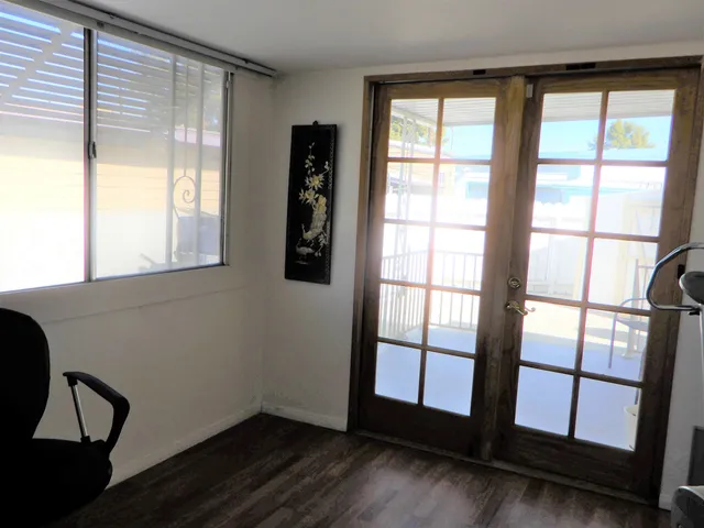 a view of an empty room with wooden floor and windows