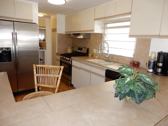 a kitchen with stainless steel appliances kitchen island granite countertop a stove a sink and a refrigerator