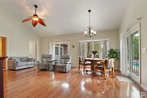 a dining room with wooden floor a chandelier a glass table and chairs