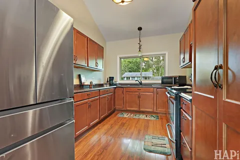 a kitchen with stainless steel appliances granite countertop a refrigerator a sink dishwasher a stove and white countertops with wooden floor