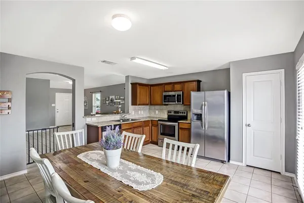 a kitchen with stainless steel appliances granite countertop a refrigerator a stove a sink a dining table and chairs