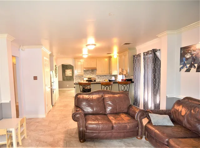 a living room with furniture and a refrigerator