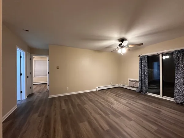 a view of an empty room with wooden floor and a ceiling fan