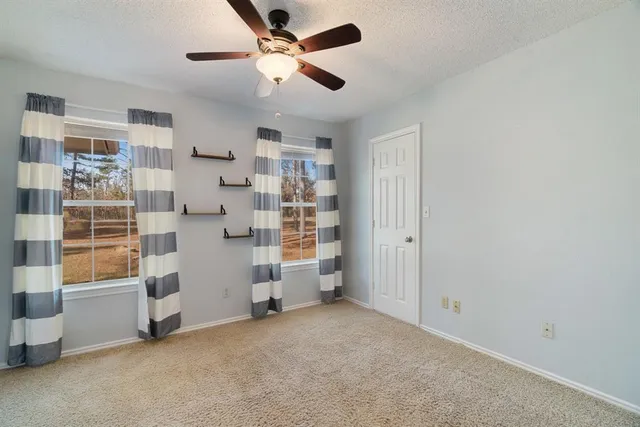 an empty room with a ceiling fan and windows